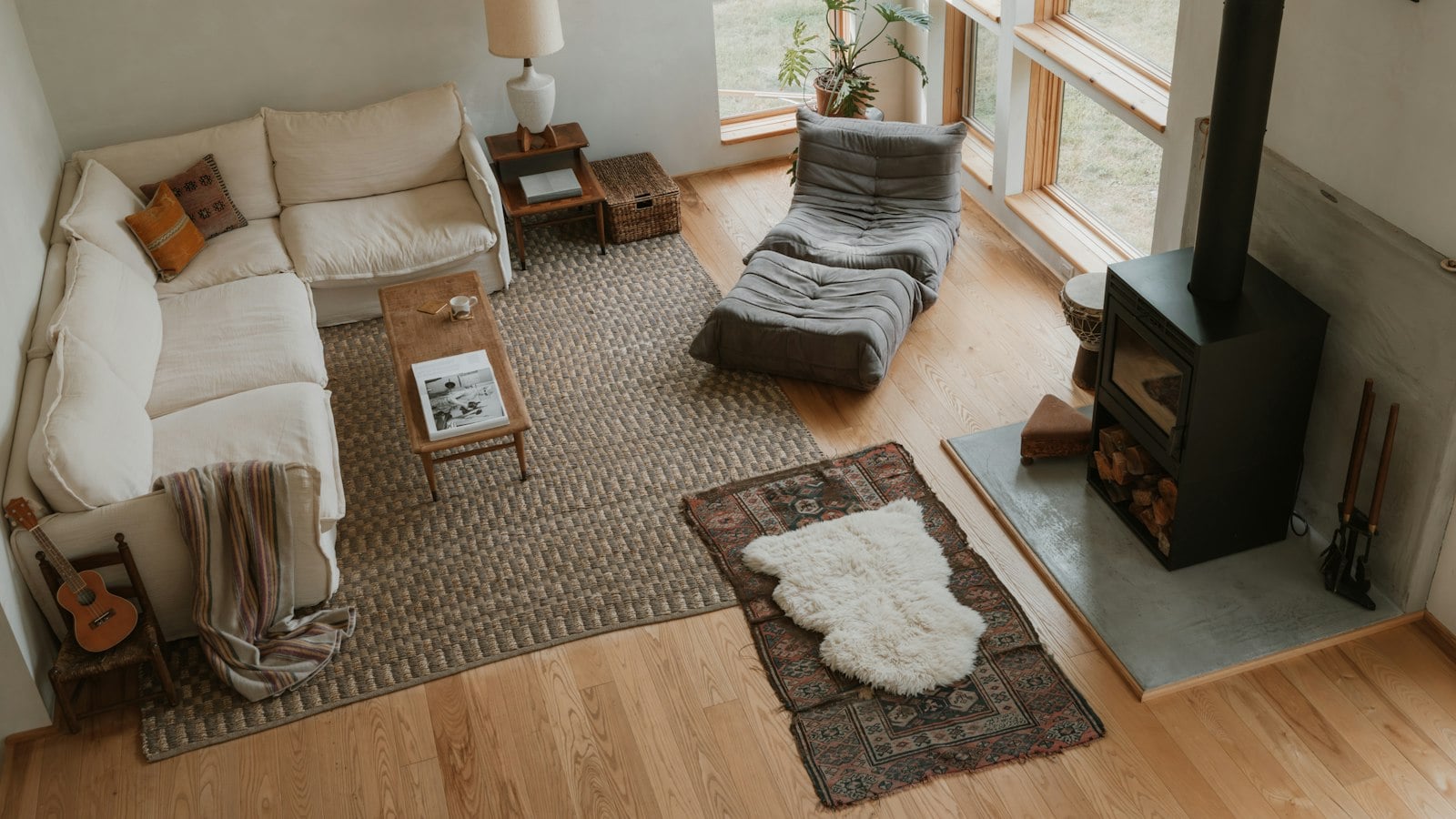 Overhead view of a living room where a hardwood floor meets a large woven rug, a patterned runner and a sheepskin (photo: Clay Banks / Unsplash)