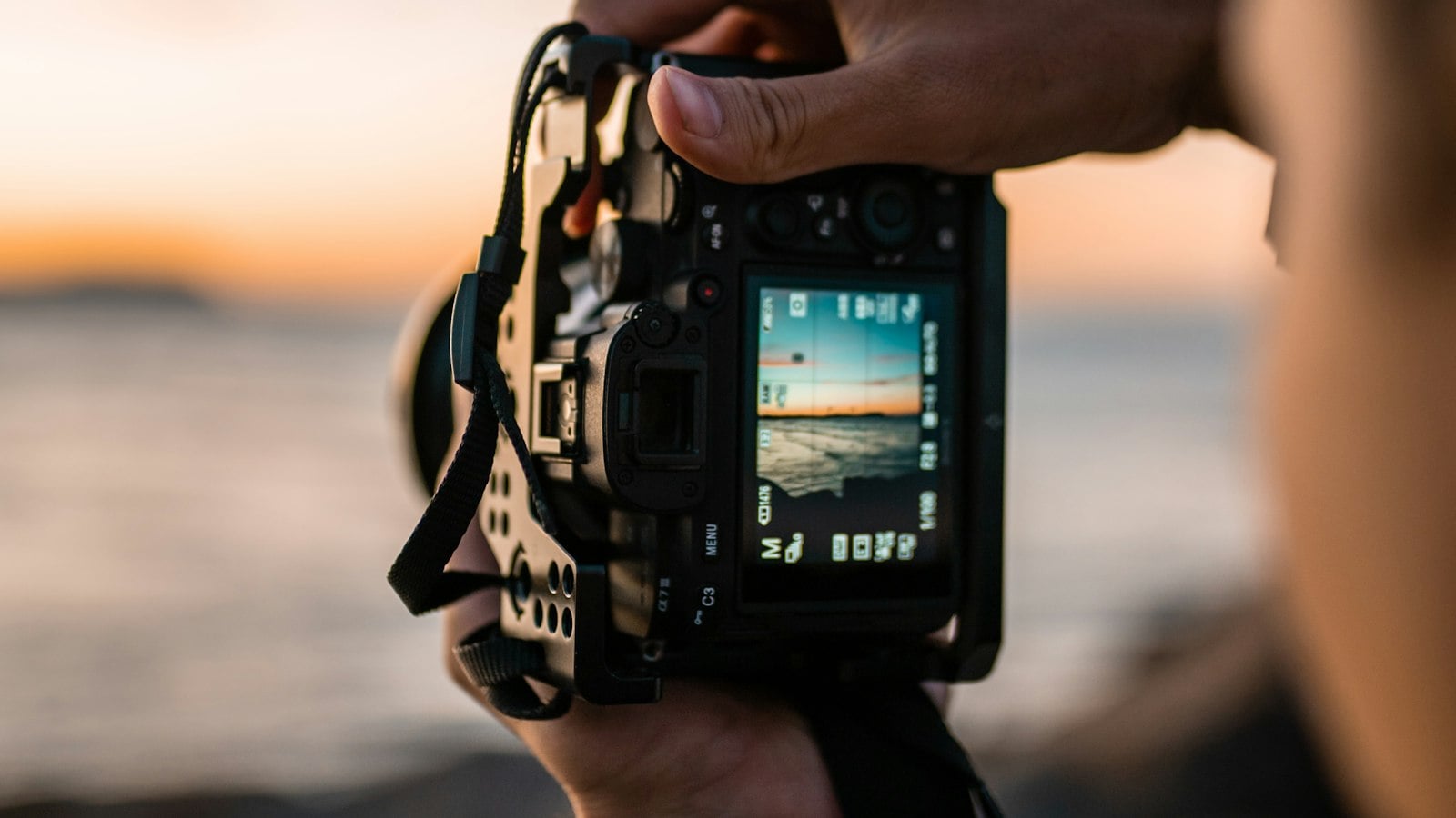 A hand framing a sunset on a camera rear screen (photo: BAILEY MAHON / Unsplash)