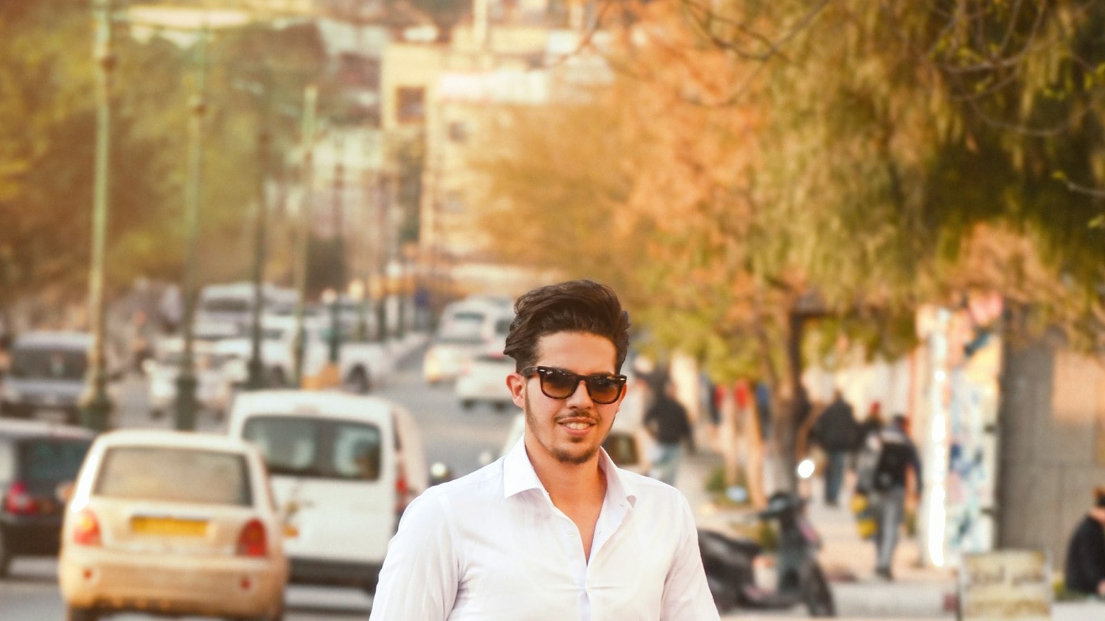 A man in a white shirt and ripped jeans walking down a street (photo: Fares Hamouche / Unsplash)
