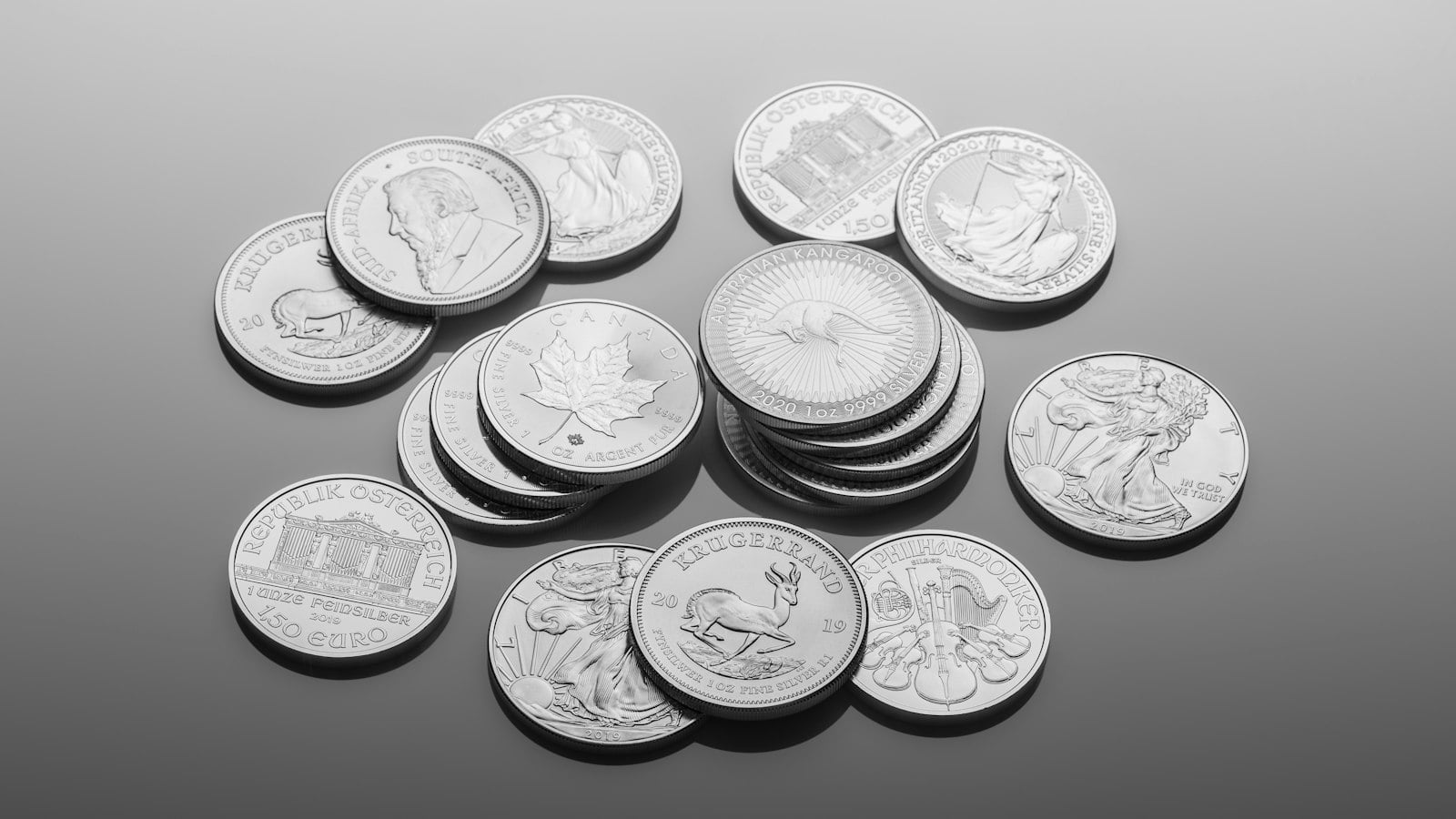 Silver coins scattered on a grey surface (photo: Zlaťáky.cz / Unsplash)