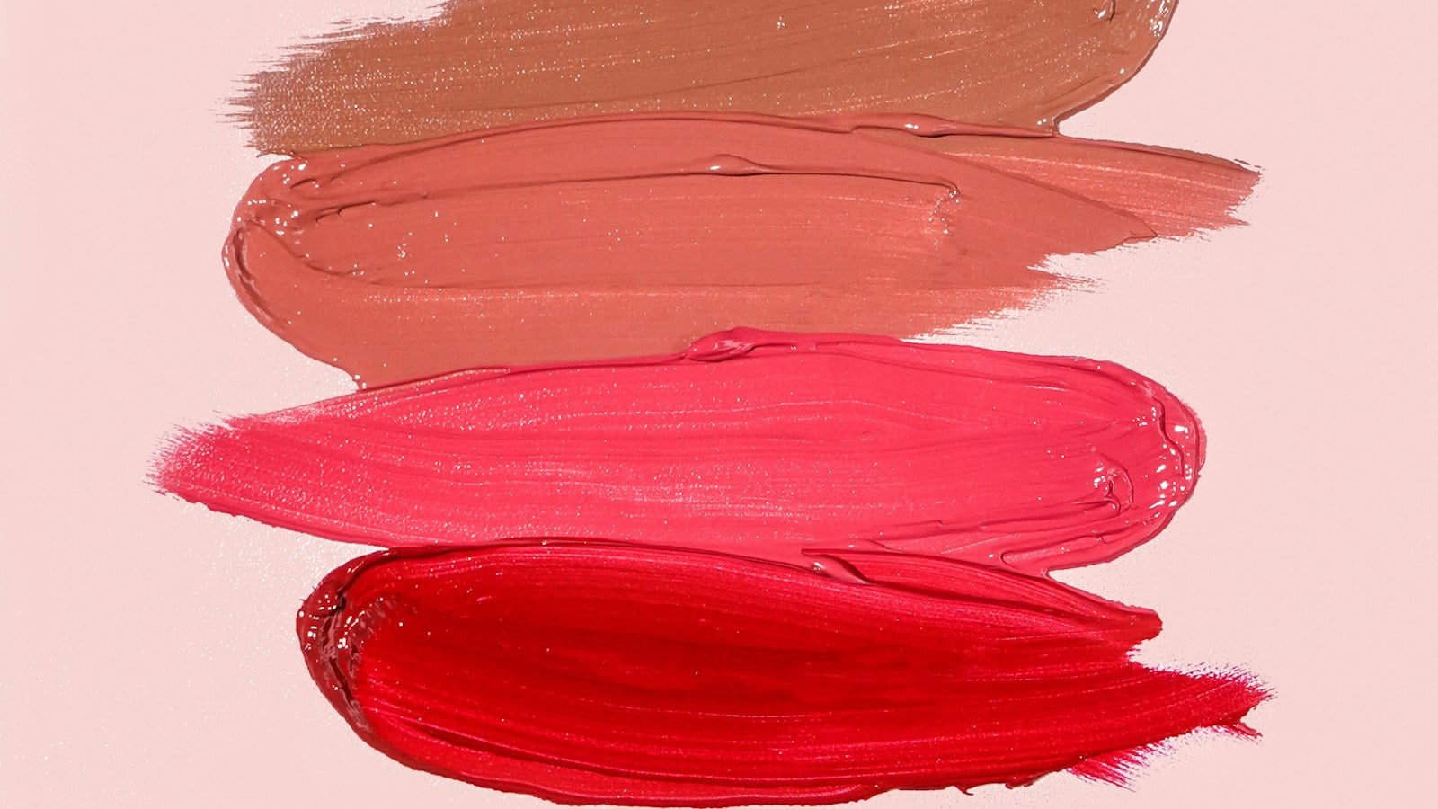 Swatches of pink, coral and red lip color on a pale background (photo: Ashley Piszek / Unsplash)
