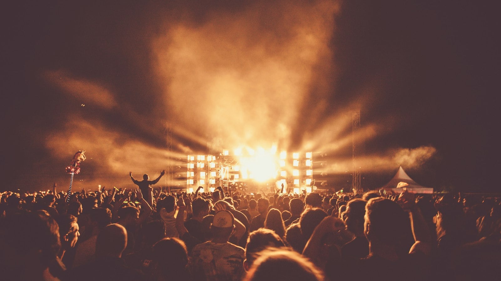 A large crowd at an outdoor music festival facing a lit stage (photo: Yvette de Wit / Unsplash)