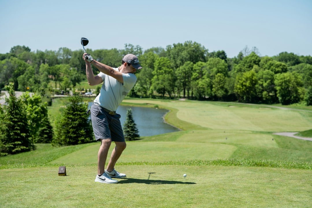 A golfer follows through on a drive from an elevated tee overlooking a pond